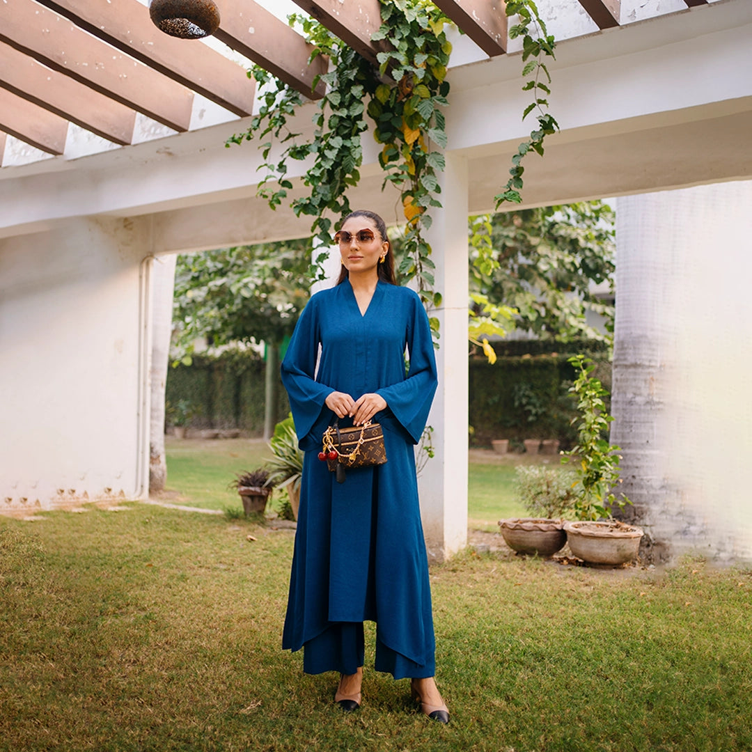 Woman in a blue dress standing under a pergola with greenery