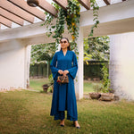 Woman in a blue dress standing under a pergola with greenery