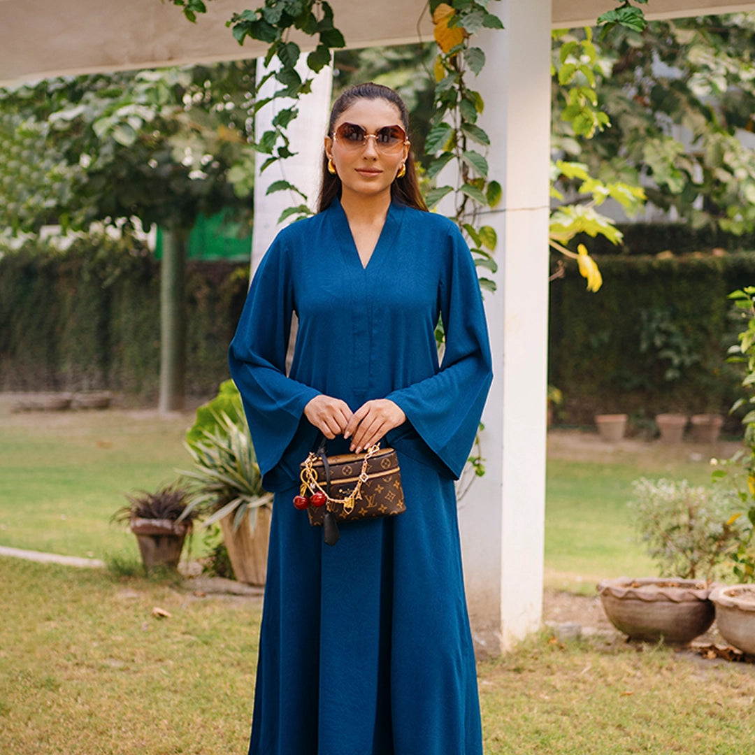 Woman in a blue dress holding a handbag in an outdoor setting