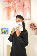 Woman holding a book titled '1913' by Ph. D. James in front of a colorful abstract painting.